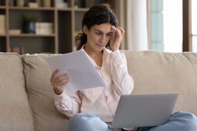 a person sitting on a couch looking at a paper.