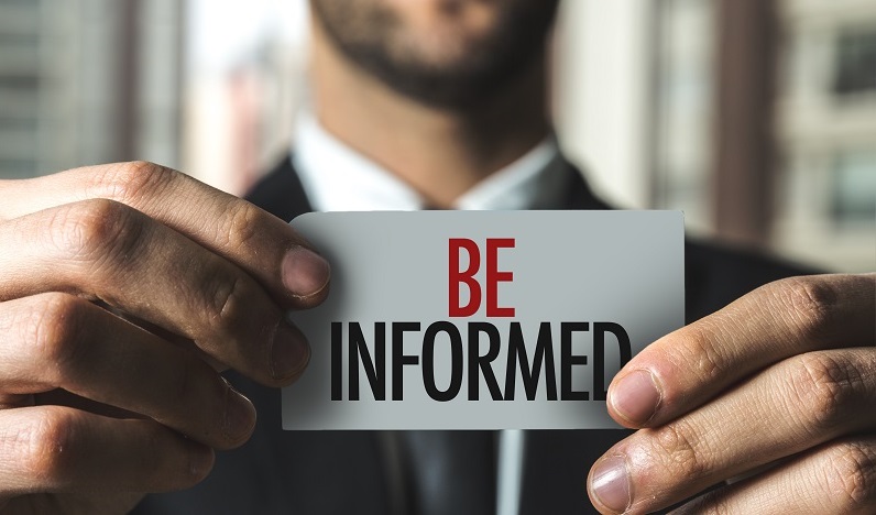 a person holding a sign. Containing the words: be informed