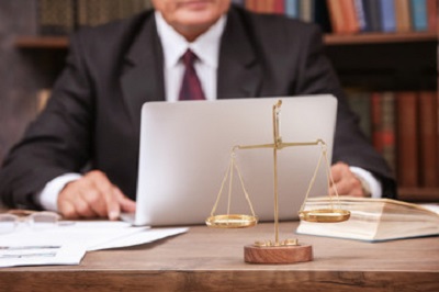 a person in a suit sitting at a desk with a laptop.