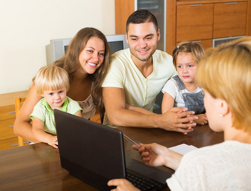 a family sitting at a table with a laptop.