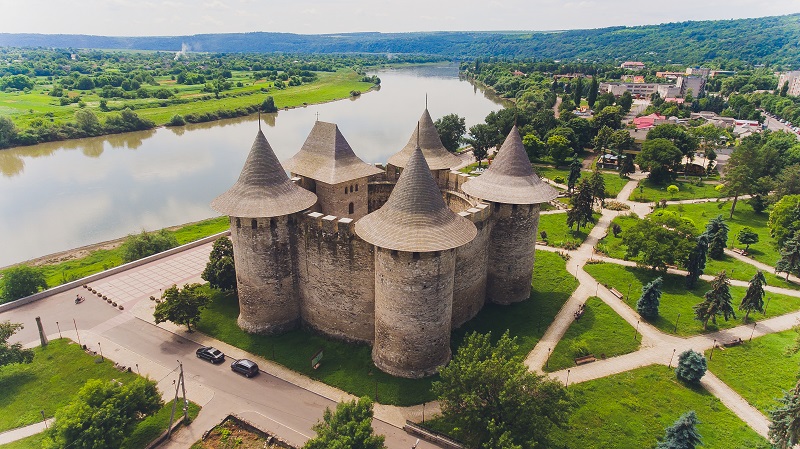 a castle with a river and trees.