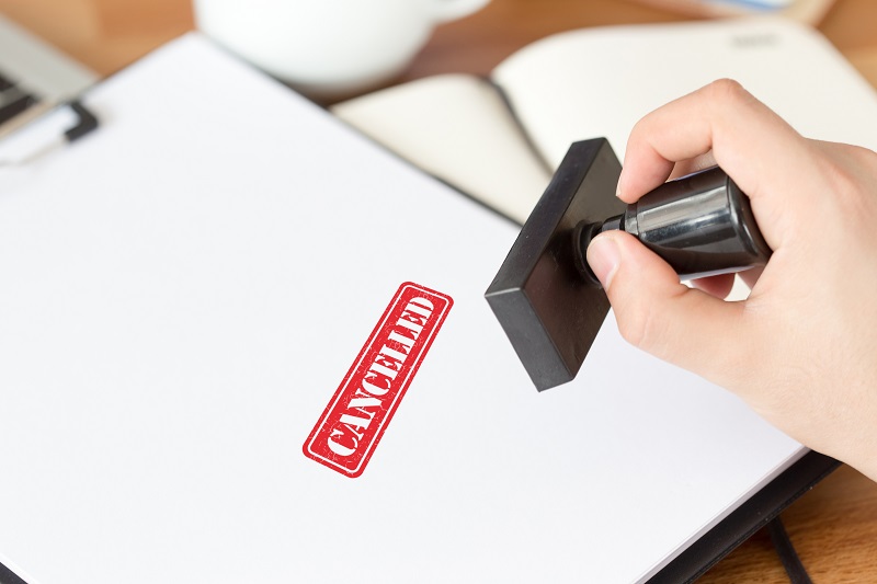 A rubber stamp and pamphlets. The stamp is stamping cancelled on a pamphlet.