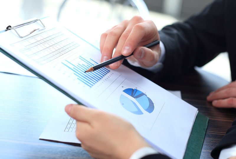 a person holding a pencil and looking at a graph.