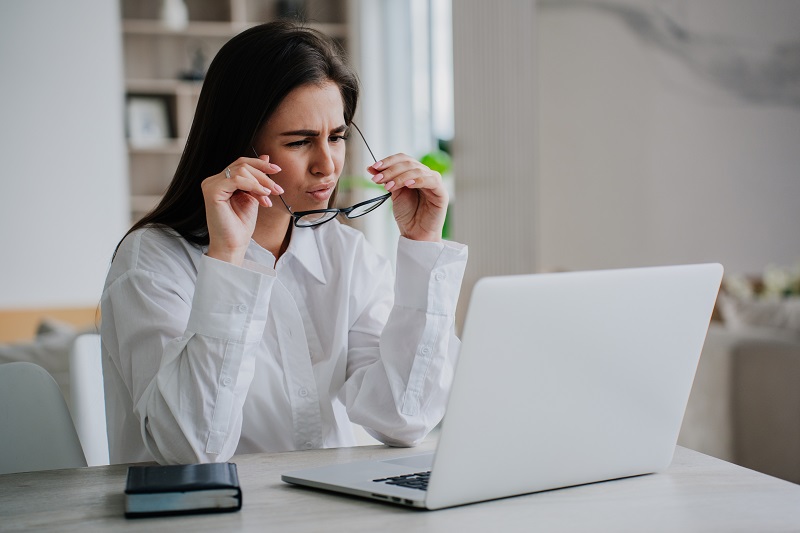 A women using a computer adjusting her glasses.