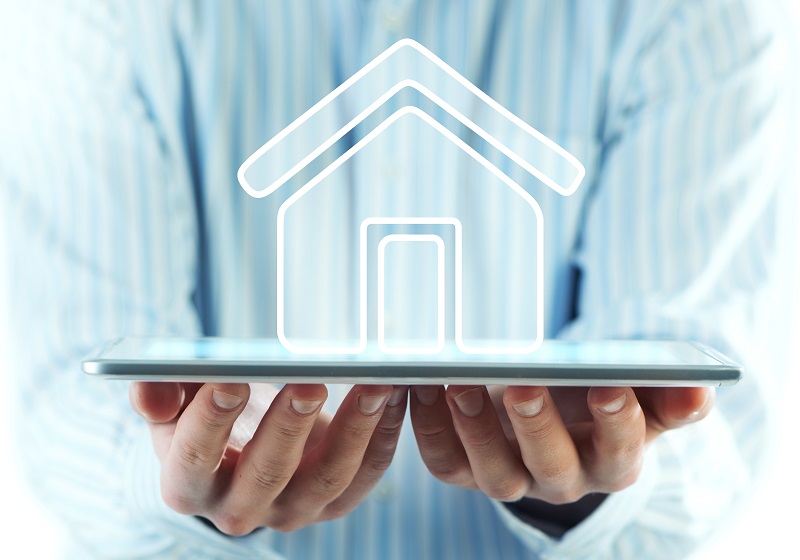 a person holding a tablet with a house icon.