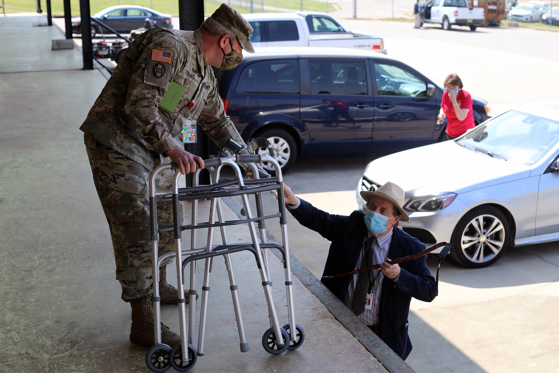 a person in a mask helping a person with a walker.